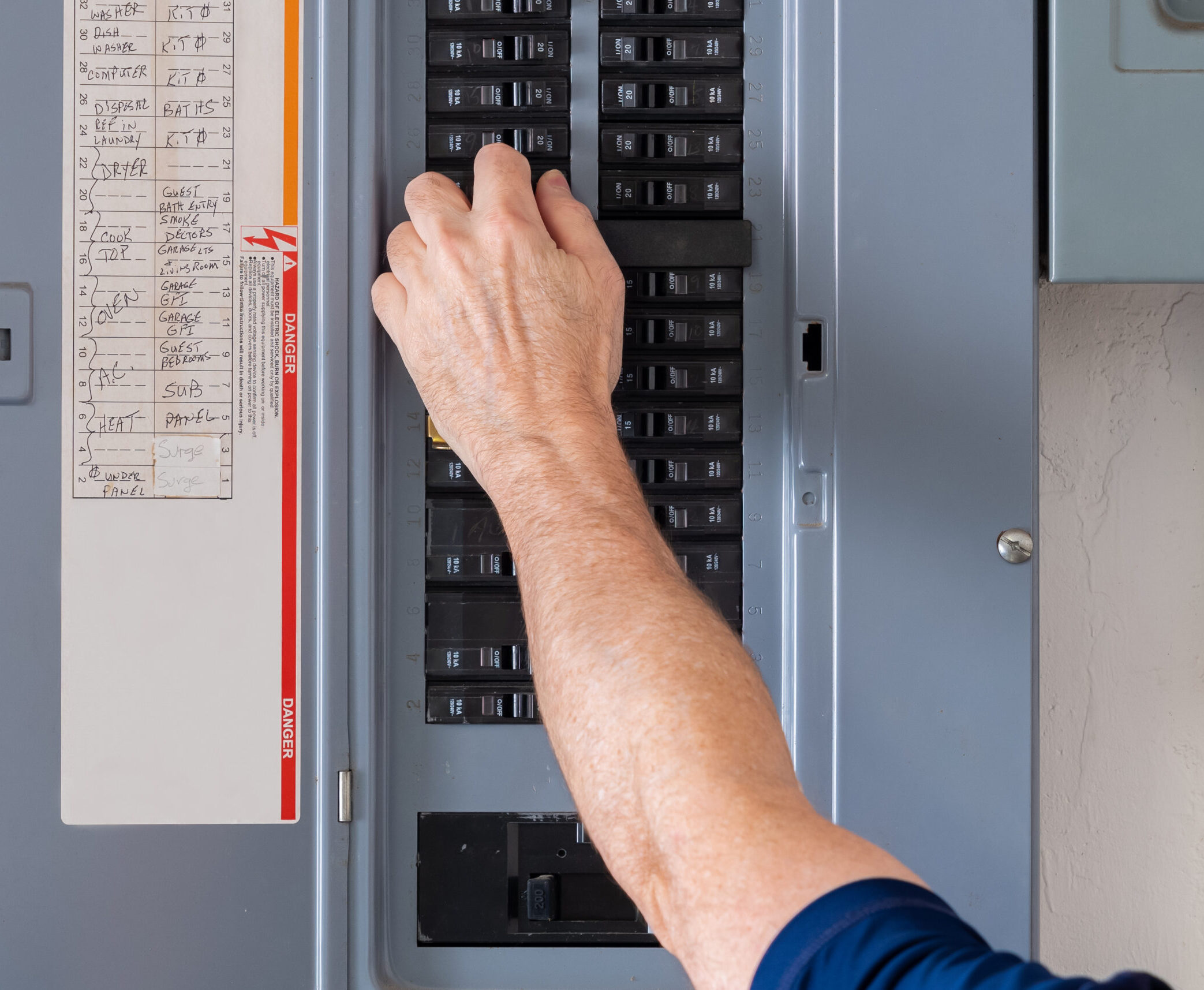 Resetting tripped breaker in residential electricity power panel. Electrician turning off power for electrical outlet at circuit breaker box.